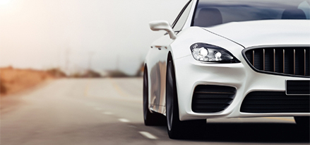 White premium-looking car driving towards the viewer on the highway.