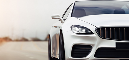White premium-looking car driving towards the viewer on the highway.