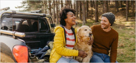Two friends talking in truck bed with a golden-colored dog