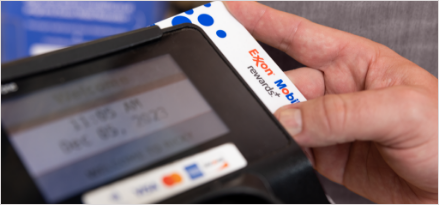 Person swiping Exxon Mobil Rewards+ gas card to earn points on in-store purchases